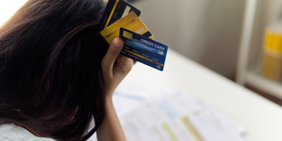 credit debt consolidation a woman holds her forehead with 3 credit cards in hand