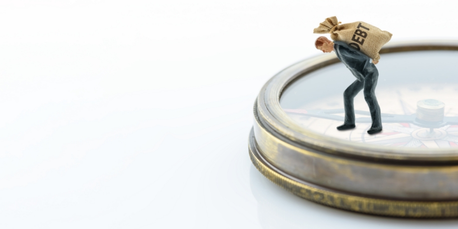 debt navigation a tiny figurine holds a bag of debt, standing atop a compass