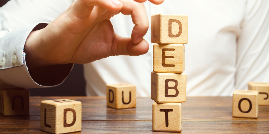 man knocking down blocks spelling debt man knocking down blocks spelling debt