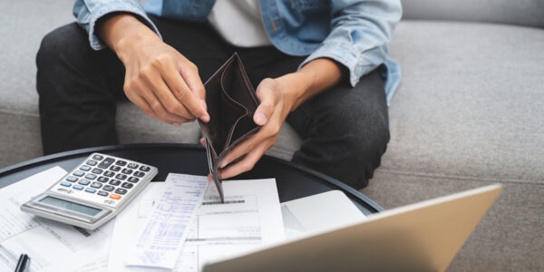 man looking at bills with an empty wallet